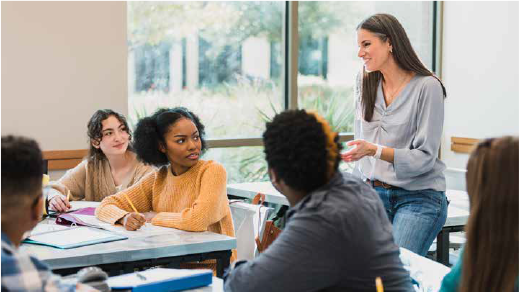 Female teacher in a classroom talking with the students looking at her